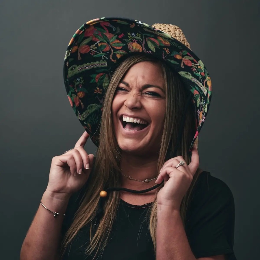 A team member laughing in a straw sun hat during a studio portrait session