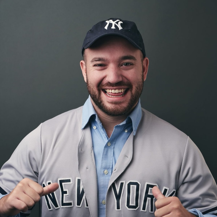 A team member in a New York Yankees jersey and cap giving two thumbs up