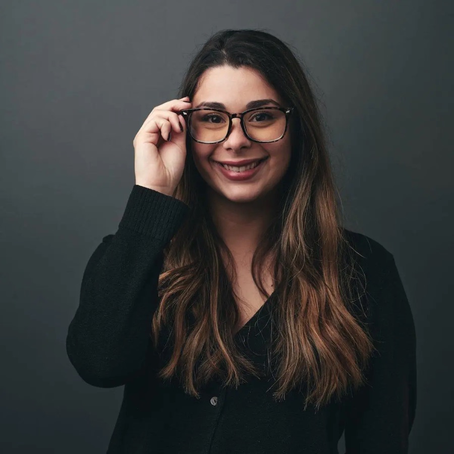 A team member smiling and adjusting her glasses in a studio portrait